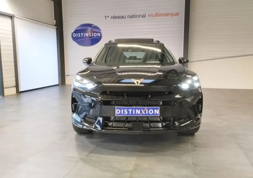 Vue frontale d'un CUPRA Formentor noir métal 2026 avec logo cuivré et phares LED allumés en intérieur showroom.