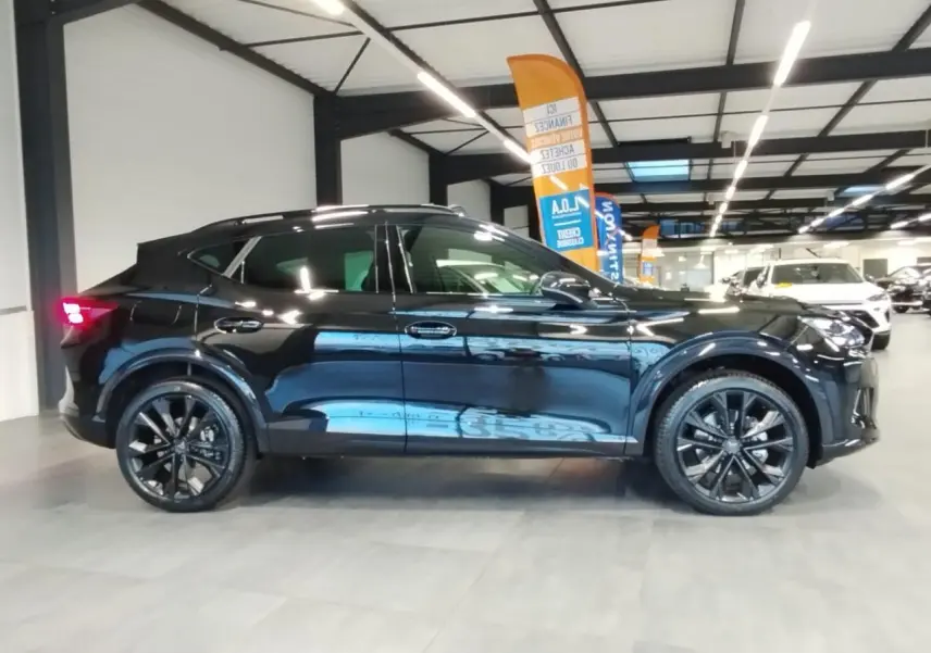 Vue latérale gauche d'un CUPRA Formentor noir métal avec jantes alliage noires et toit ouvrant panoramique en intérieur showroom.