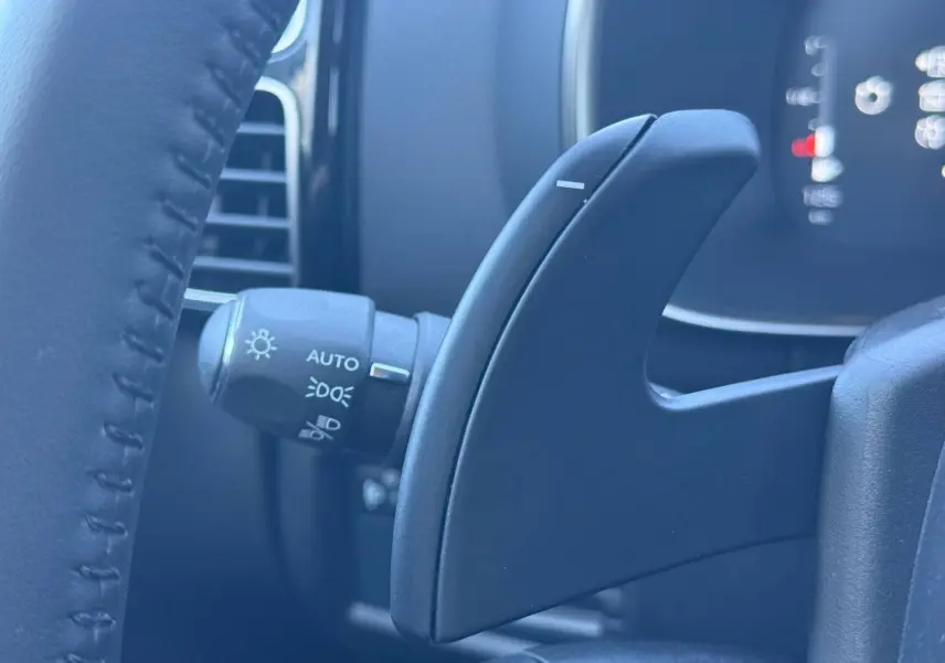Gros plan sur la palette de changement de vitesses derrière le volant du Citroën C5 Aircross noir, avec commandes d’éclairage visibles.