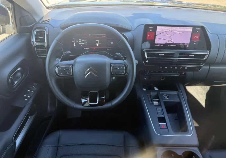 Vue intérieure frontale du poste de conduite noir du Citroën C5 Aircross avec écran tactile et volant multifonction.