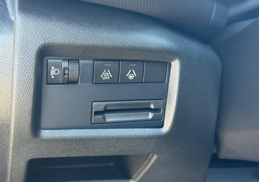 Gros plan sur les commandes de réglage des phares et d'aides à la conduite dans l'habitacle noir du Citroën C5 Aircross.