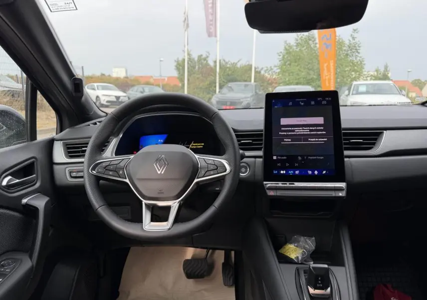 Vue intérieure frontale du tableau de bord et volant Renault Symbioz gris cassiope avec écran tactile vertical et commandes au volant.