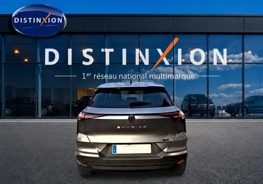Vue arrière du Renault SYMBIOZ gris cassiope, soulignant ses feux LED fins et son logo centré devant une vitrine Distinxion.