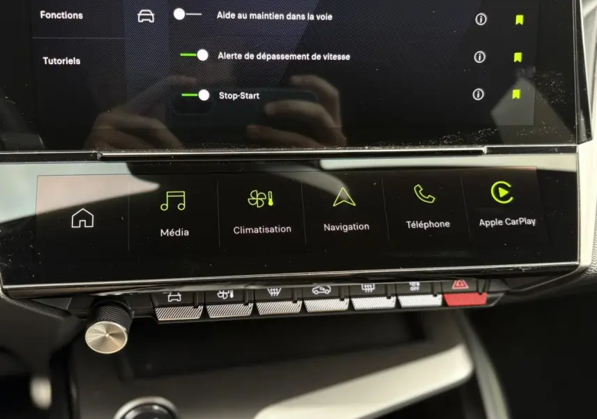 Vue rapprochée de l'écran tactile central et des commandes tactiles du Peugeot 308 2024 blanc, affichant navigation et Apple CarPlay.