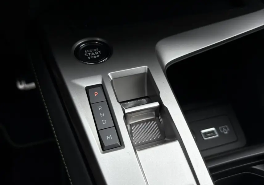Gros plan sur la console centrale argentée de la Peugeot 308 2024 avec bouton start/stop et commandes de boîte auto.