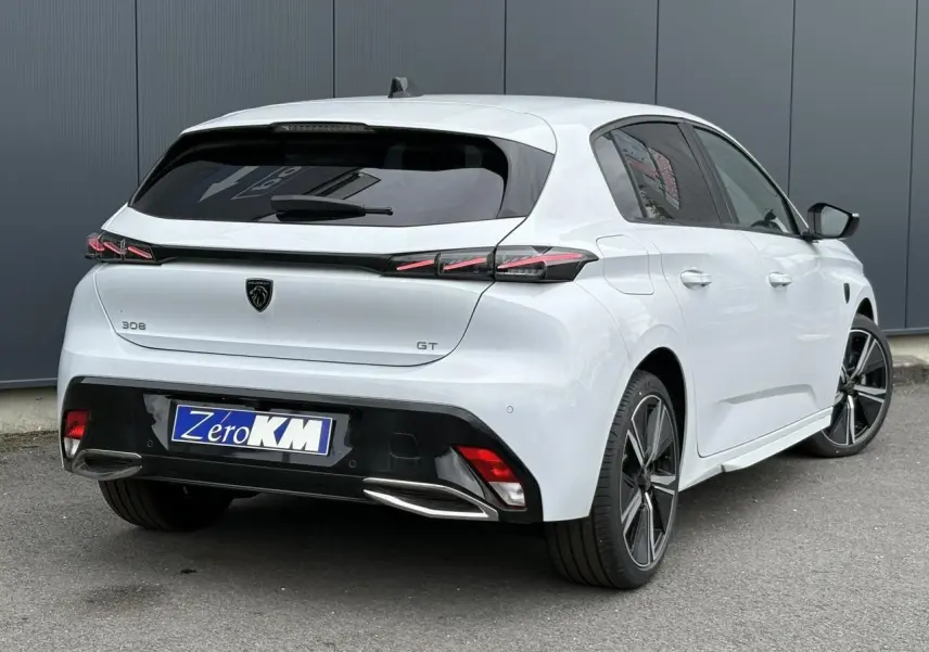 Vue 3/4 arrière droite d'une Peugeot 308 GT blanche Okenite avec feux LED et jantes alliage 18 pouces.