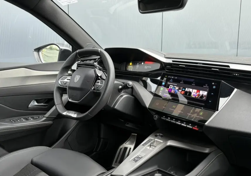 Vue intérieure côté conducteur du Peugeot 308 2024, mettant en valeur le volant cuir et l'écran tactile central.