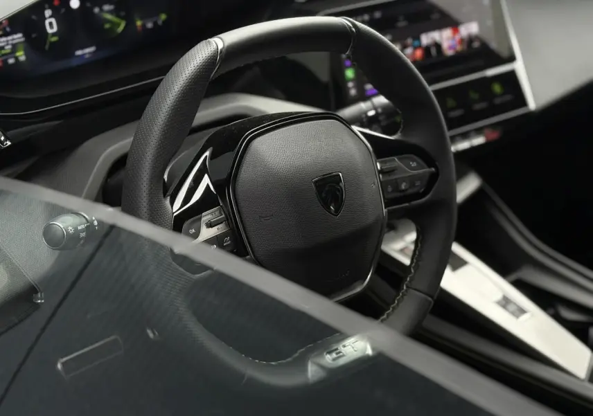 Gros plan sur le volant cuir noir de la Peugeot 308 GT 2024, avec commandes intégrées et logo central.