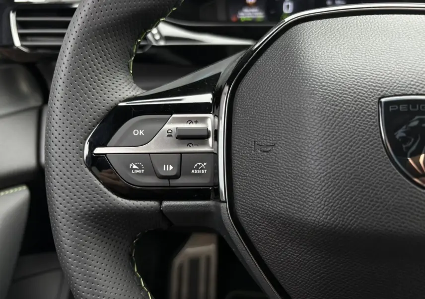 Gros plan sur le volant cuir perforé avec commandes intégrées du Peugeot 308 GT 2024 blanc Okenite.