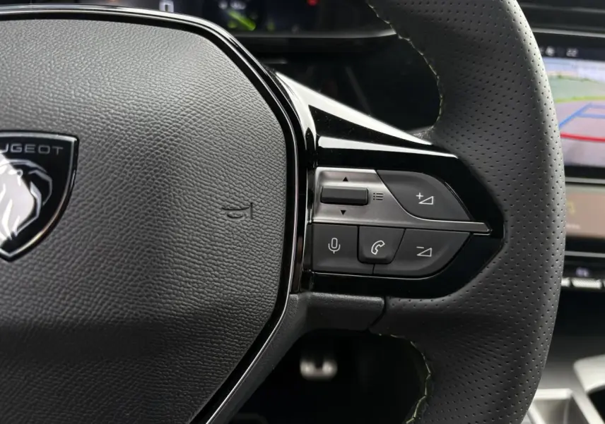 Gros plan sur le volant cuir perforé de la Peugeot 308 2024, avec commandes vocales et téléphone intégrées.