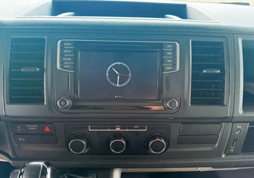 Vue rapprochée du tableau de bord noir du Volkswagen Transporter L1H1 2018 avec écran central et commandes de climatisation.