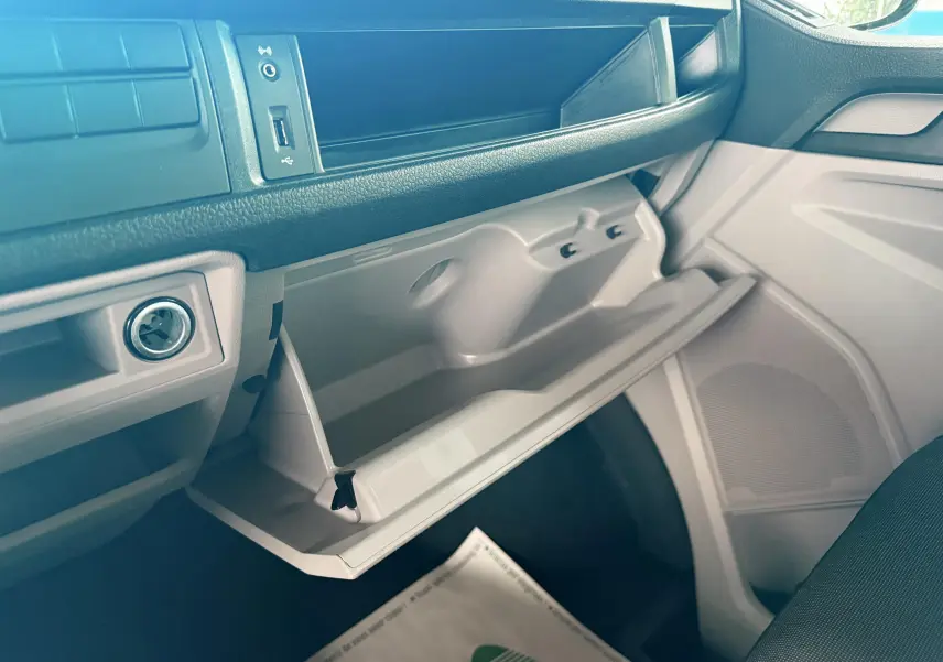 Vue intérieure côté passager du Volkswagen Transporter L1H1 2018, boîte à gants ouverte, tableau de bord gris clair.