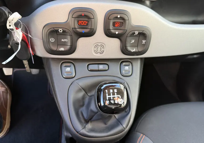Vue rapprochée de la console centrale grise de la Fiat Panda City Cross 2023 avec levier de vitesse manuel et commandes de climatisation.