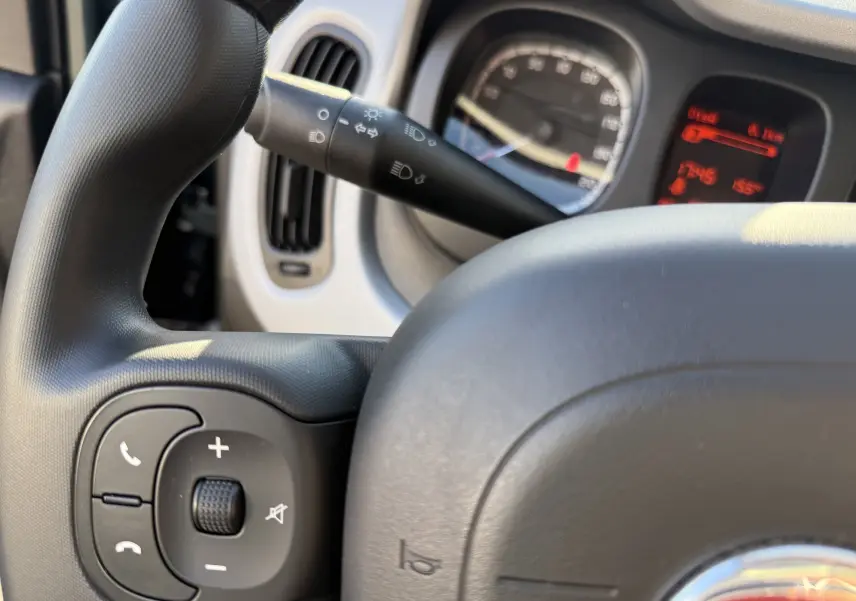 Gros plan sur le volant noir de la Fiat Panda City Cross 2023 avec commandes audio et tableau de bord partiellement visible.