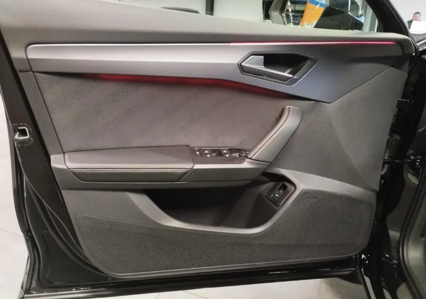 Vue intérieure de la porte avant gauche noire du CUPRA Formentor 2026 avec éclairage d'ambiance rouge et finitions suédine.