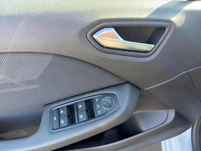 Vue rapprochée de la porte avant gauche de la Renault Clio Esprit Alpine gris clair, avec commandes électriques des vitres et poignée intérieure.