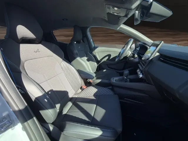 Intérieur de la Renault Clio Esprit Alpine E-Tech 2025, vue côté gauche, sièges sport gris avec logo Alpine et écran tactile central.