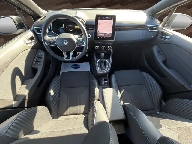 Vue intérieure avant de la Renault Clio Esprit Alpine E-Tech 2025, tableau de bord noir avec écran tactile vertical et volant multifonctions.