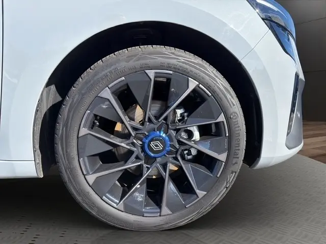 Gros plan sur la roue avant droite d'une Renault Clio Esprit Alpine gris clair, avec jante noire au design géométrique.