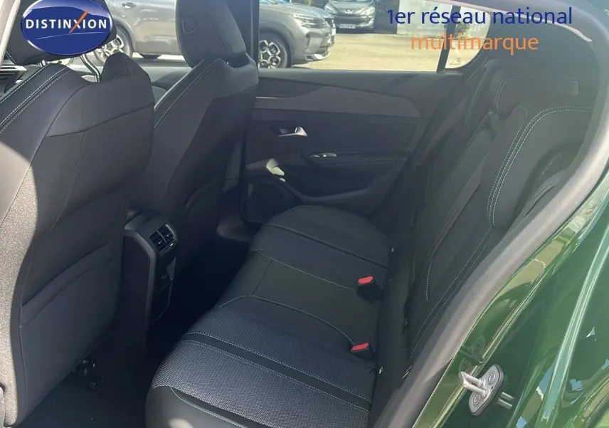 Vue côté droit arrière sur l'intérieur noir avec surpiqûres vertes d'une Peugeot 308 1.2 Hybrid 136ch finition Allure vert olivine métal.
