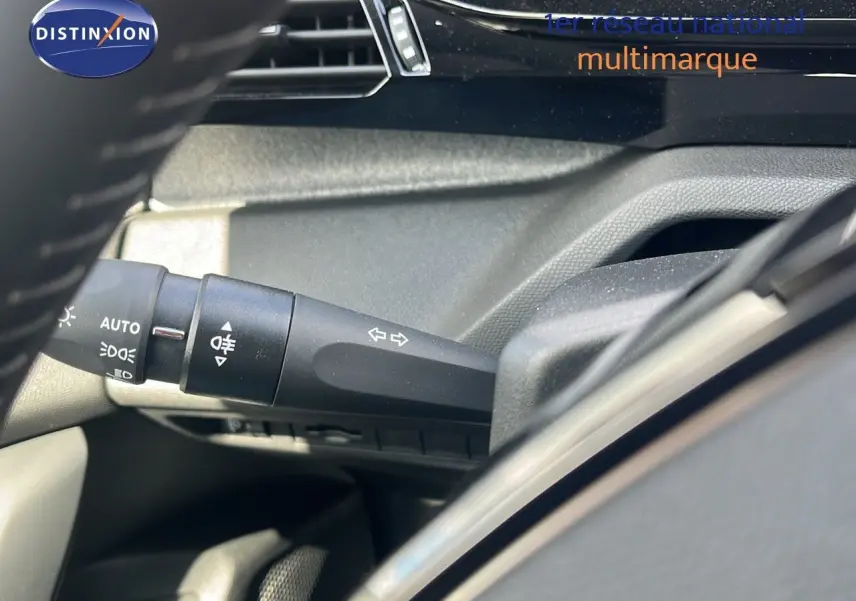 Détail de la commande des clignotants et feux sur le côté gauche du volant d'une Peugeot 308 vert olivine hybride 2024