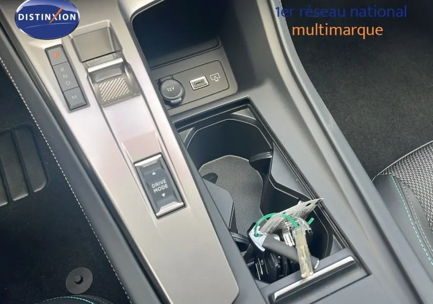 Gros plan sur la console centrale de la Peugeot 308 hybride 2024, avec levier de vitesses et porte-gobelets noir.