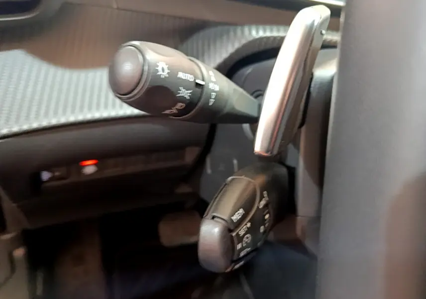 Gros plan sur les commandes au volant de la Peugeot 2008 gris clair, mettant en valeur les leviers multifonctions.