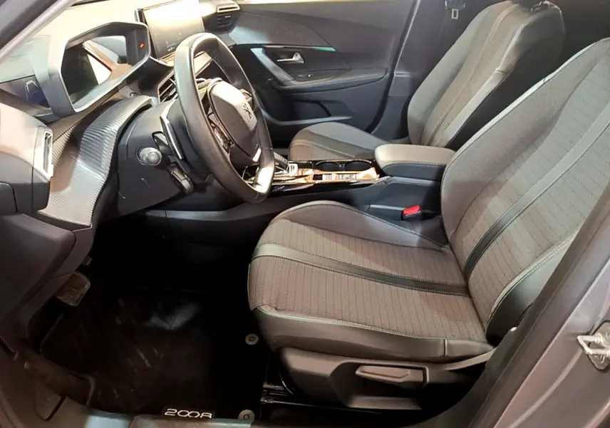 Intérieur avant droit du Peugeot 2008 gris clair 2021, sièges tissu avec surpiqûres et tableau de bord moderne.