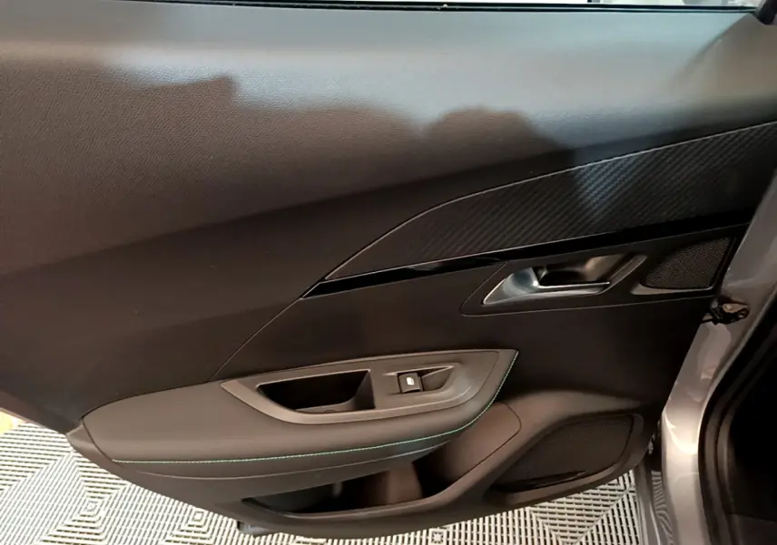 Vue rapprochée de la porte côté gauche gris clair du Peugeot 2008 avec garniture noire et poignée métallique.