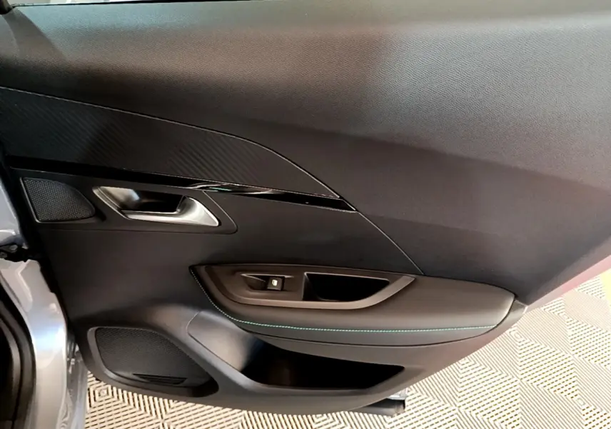 Vue intérieure côté gauche de la porte avant grise claire du Peugeot 2008 avec garniture noire et surpiqûres bleues.