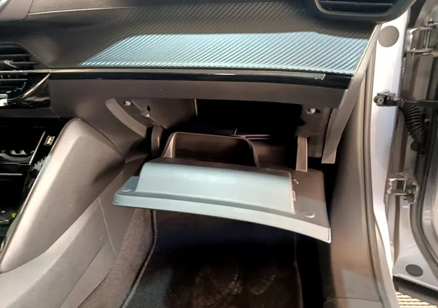 Vue intérieure côté passager du Peugeot 2008 gris clair 2021 avec boîte à gants ouverte et tableau de bord noir.