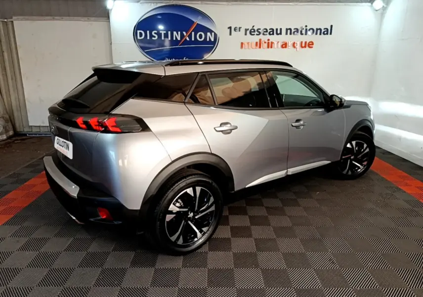 Peugeot 2008 gris clair vue 3/4 arrière droit, avec feux arrière LED et jantes noires distinctives.