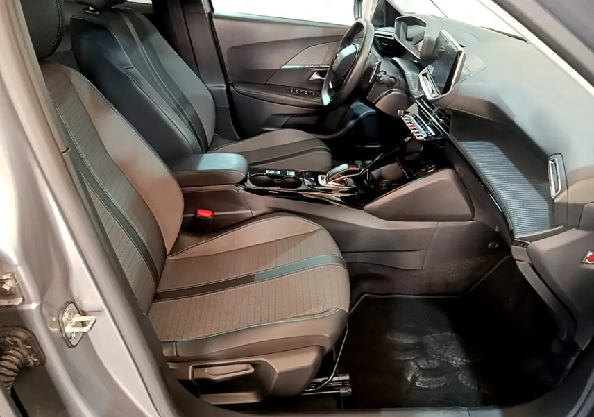 Intérieur avant droit du Peugeot 2008 gris clair, sièges tissu avec surpiqûres et tableau de bord moderne tactile.