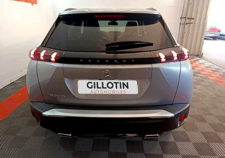 Vue arrière d'un Peugeot 2008 gris clair avec feux LED caractéristiques et double sortie d'échappement visible.