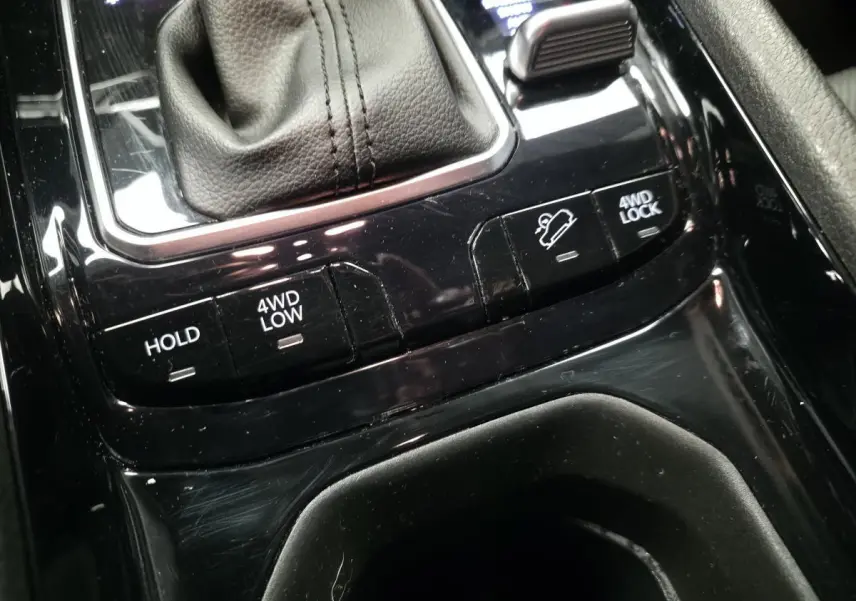 Gros plan sur la console centrale noire du Jeep Compass 2024 avec commandes 4WD et frein de stationnement automatique.