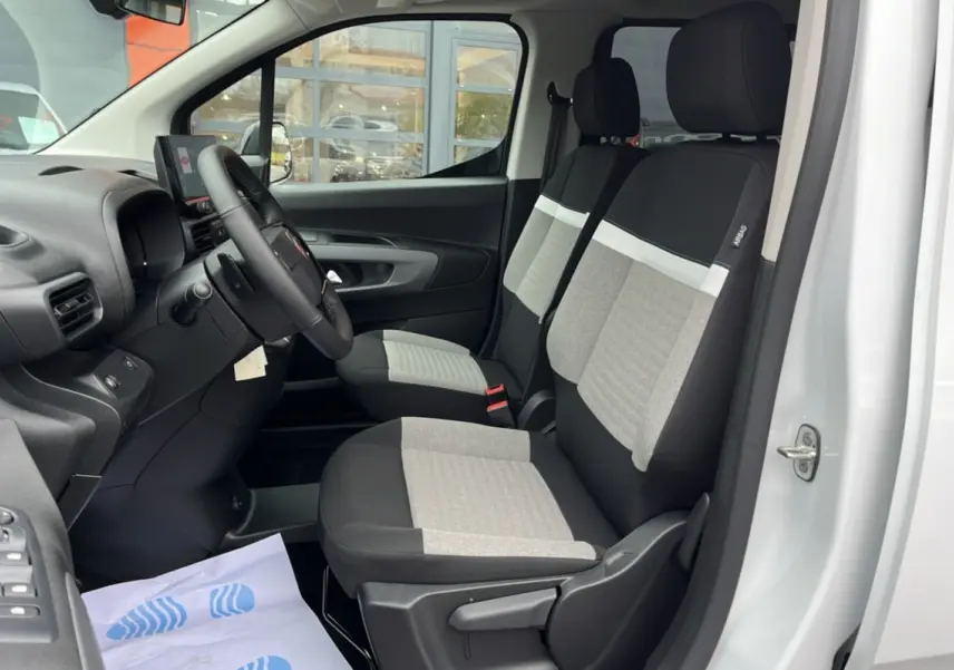 Vue intérieure côté conducteur du Citroën Berlingo Kaolin white 2026, montrant les sièges avant bicolores et le volant multifonctions.