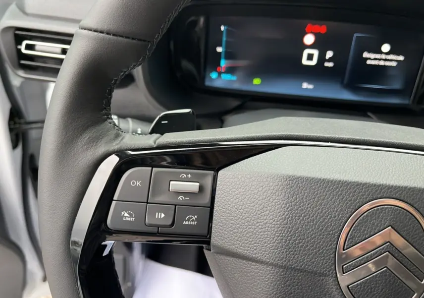 Gros plan sur le volant cuir noir du Citroën Berlingo blanc, avec commandes multifonctions et tableau de bord numérique.