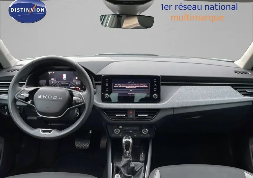 Vue intérieure frontale du tableau de bord noir et gris du Skoda Kamiq 2025 avec écran tactile central et volant multifonction.