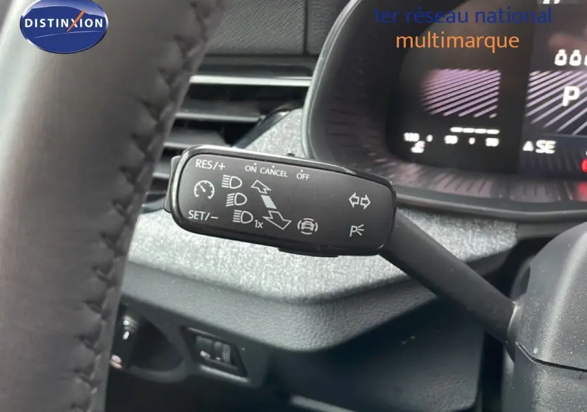 Gros plan sur la commande de régulateur de vitesse à gauche du volant dans un Skoda Kamiq blanc glacier 2025.
