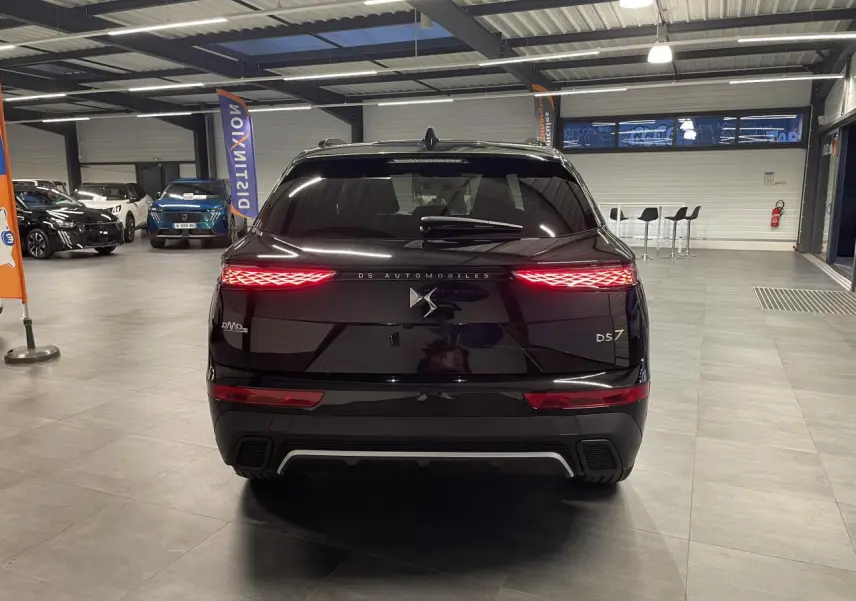 Vue arrière d'un DS7 Crossback noir métallisé avec feux arrière LED 3D et logo DS Automobiles lumineux.