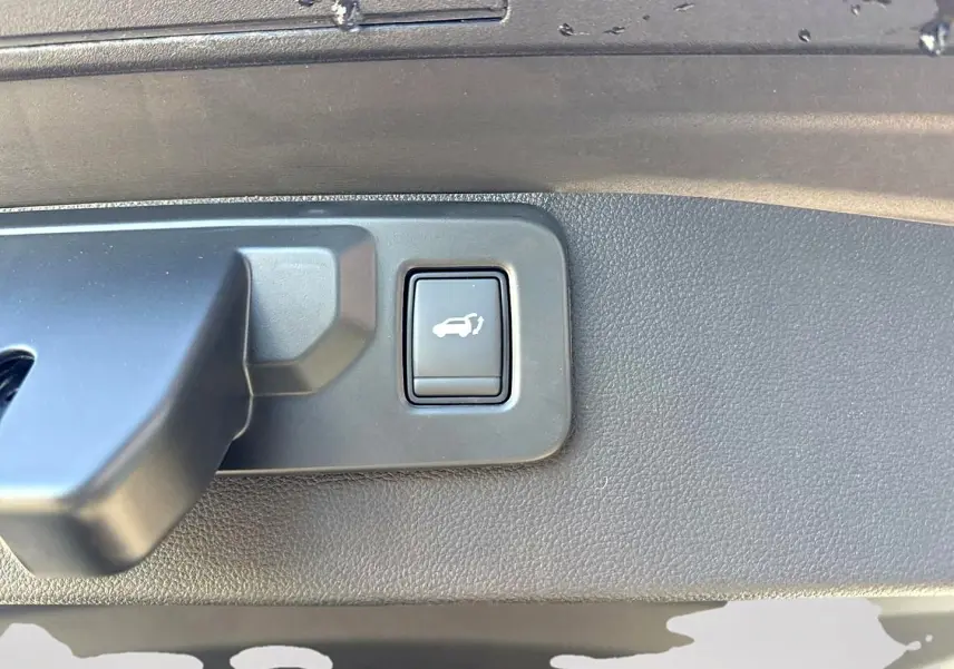 Bouton d'ouverture électrique du coffre sur le panneau intérieur d'une Renault Symbioz gris rafale.