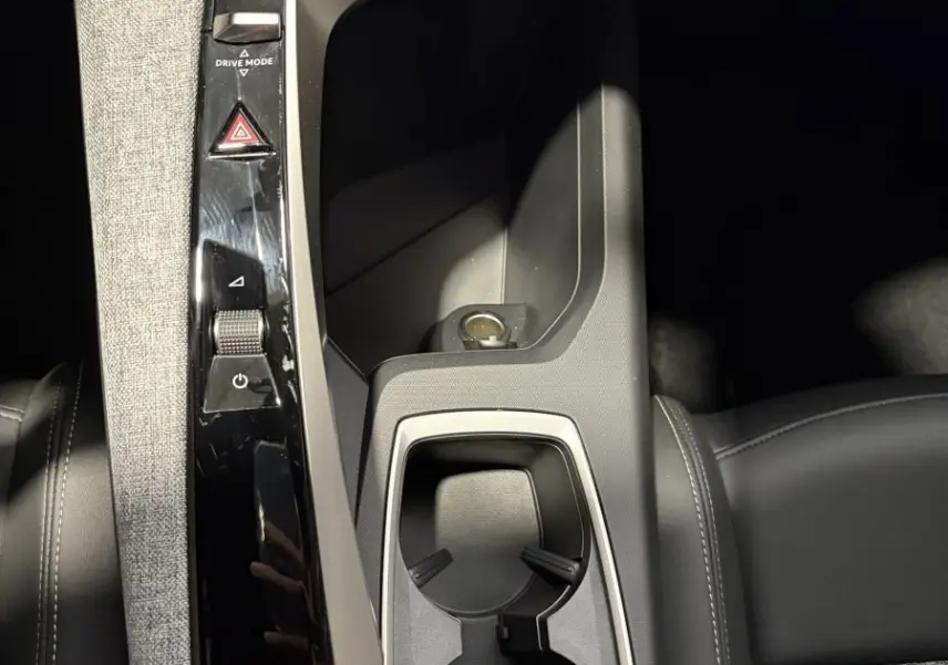 Vue plongeante sur la console centrale noire et grise du Peugeot 3008 blanc, avec porte-gobelets et commandes tactiles.