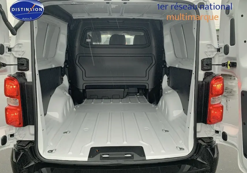 Vue arrière ouverte du Peugeot Expert Long blanc Kaolin 2023 montrant l'espace de chargement vide et les feux arrière allumés.