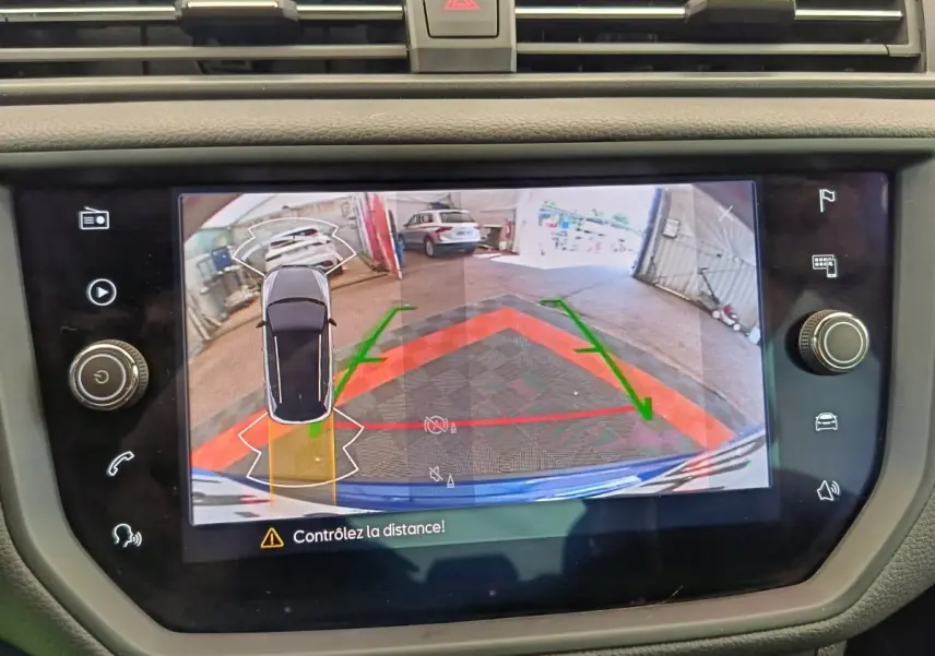 Écran tactile du système de stationnement assisté montrant la vue arrière et latérale d'une SEAT Arona bleue.
