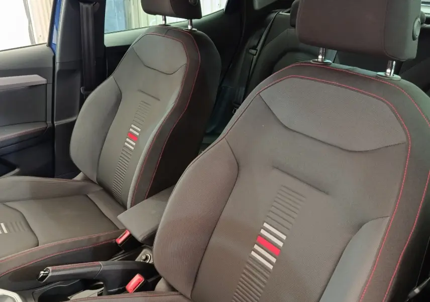 Vue intérieure rapprochée des sièges avant noirs avec surpiqûres rouges du SEAT Arona bleu 2021 finition FR.