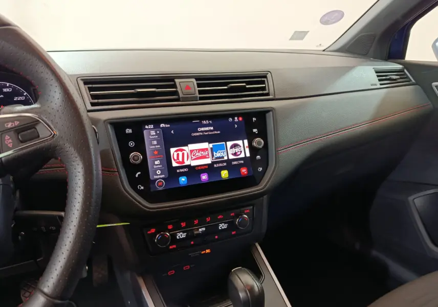 Vue intérieure côté passager du tableau de bord noir avec écran tactile et volant cuir du SEAT Arona bleu 2021.