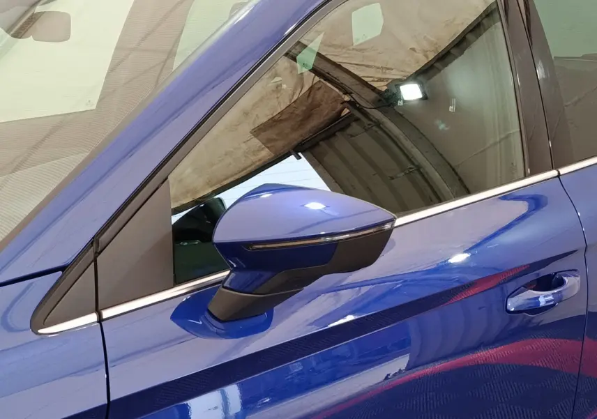 Gros plan sur le rétroviseur côté conducteur bleu d'un SEAT Arona 2021 avec poignée de porte assortie.