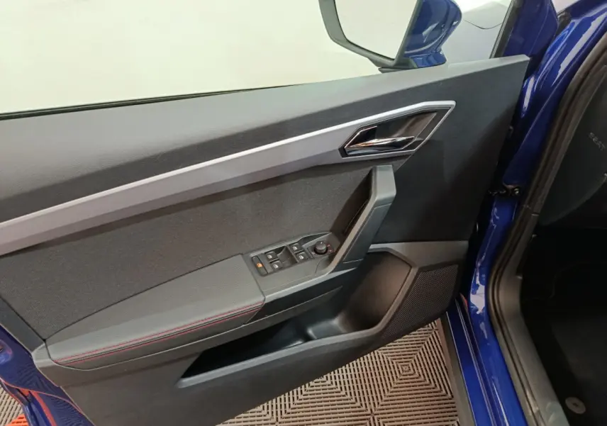 Détail de la porte côté conducteur bleu d'un SEAT Arona 2021 avec commandes de vitres et rétroviseur électrique.