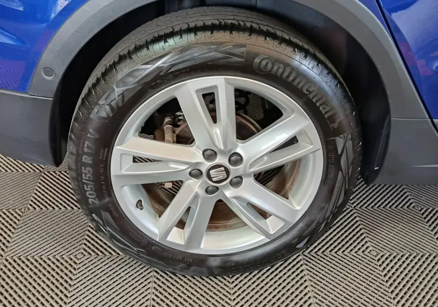 Gros plan sur la roue avant droite d'un SEAT Arona bleu, mettant en valeur la jante alliage et le pneu Continental.