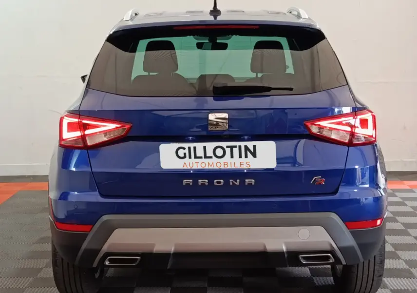 Vue arrière d'un SEAT Arona bleu 2021 finition FR avec feux LED et double sortie d'échappement intégrée.
